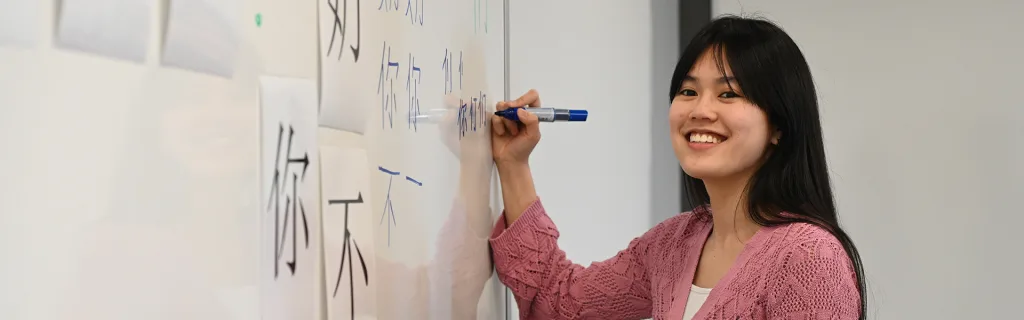 Étudiante écrivant des caractères chinois au tableau