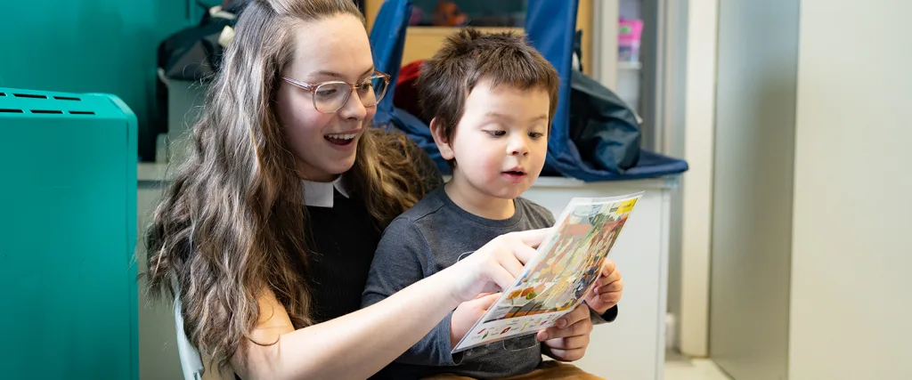 Enfant qui regarde une image avec son éducatrice